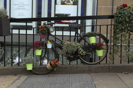 A parked bike at a fence with some flower pots attachedの写真素材