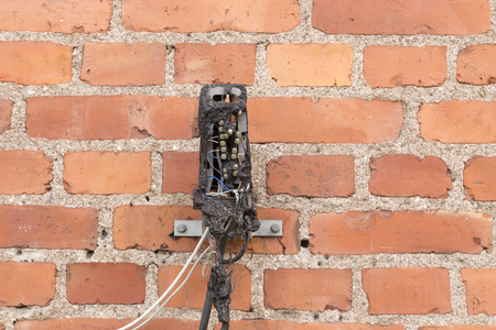 An old telephone switch box that have been destroyed in a fire with a brick wall in the backgroundの写真素材