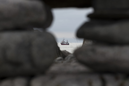 A ship on the ocean sighted between some stones