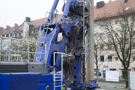 An industrial crane with hydraulics in front of some buildingsの写真素材