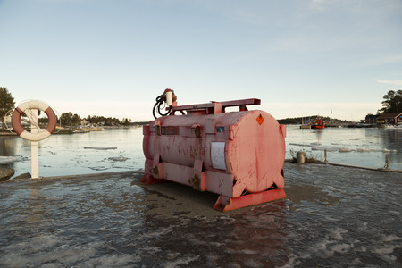 A gas tank on a pier with the ocean and a pilot boat in the backgroundの写真素材