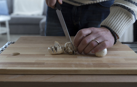 A man cutting mushrooms on a cutting boardの写真素材