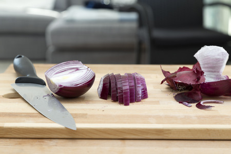 A partly cutted red onion on a cutting board and a knifeの写真素材