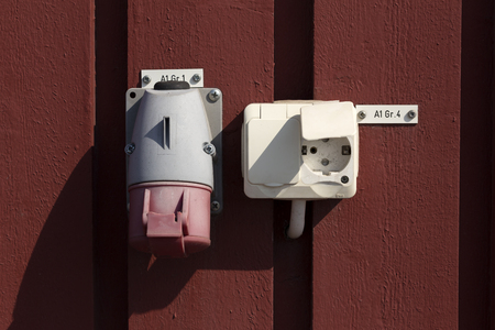 Some power plugs on a wall with some information on signs