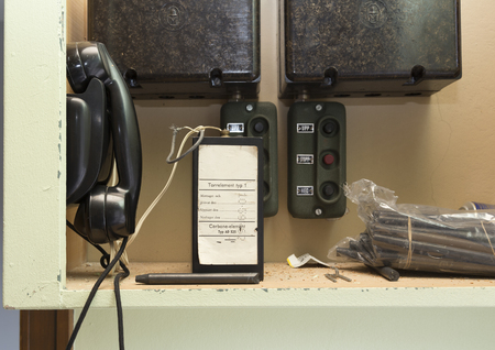 Backelite phone on a wal with a broken cord in the backgroundのeditorial素材