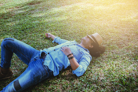 Asian man travel relax in the holiday. Sleep relax on the lawn on the mountain. In Thailandの写真素材