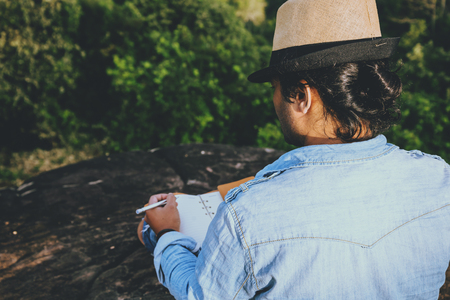 Asian man travel relax in the holiday. seats relax read books on rocky cliffs. On the Moutain. In Thailandの写真素材