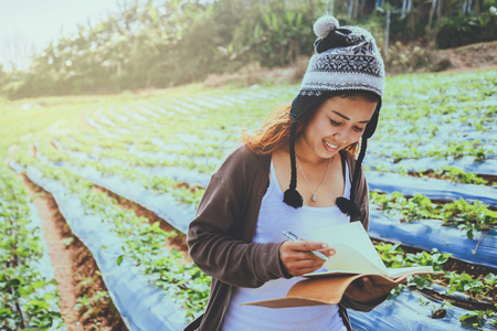 Asian women relax in the holiday. Write a note in the notebook. In the Strawberry Park on the...