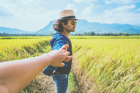 Lover women and men asians travel relax in the holiday. Lovers walk hand in hand on rice field. Thailandの写真素材