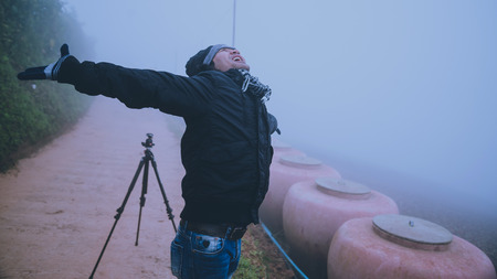 Asian man photographer relax in the holiday. Happy to travel in the holiday. During the foggy winterの写真素材