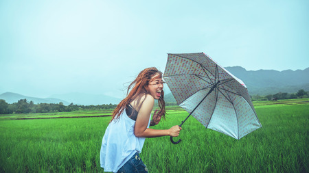 Asian women travel relax in the holiday. Women stand in rain umbrellas. On the meadow During the...