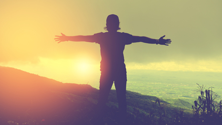 Asian man travel relax in the holiday.Standing hands on cliffs on the mountain.の写真素材