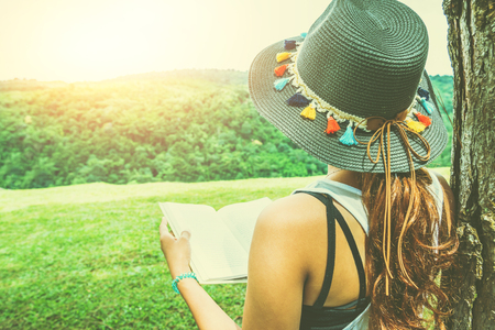Asian women relax in the holiday. Stand read books on grassland in the park.の写真素材