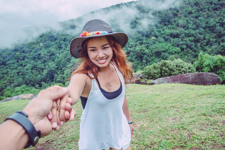Lover women and men asians travel relax in the holiday. Hold hands running on the lawn. Wild nature wood on the mountain.  の写真素材