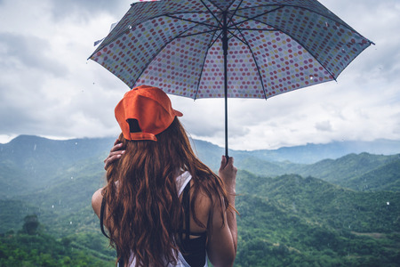 Asian women travel relax in the holiday. The women stood in rain umbrellas on the mountain. During the rainy season.Thailandの写真素材