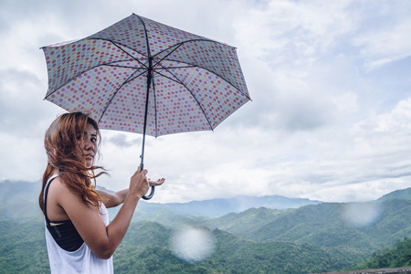 Asian women travel relax in the holiday. The women stood in rain umbrellas on the mountain. During the rainy season.Thailandの写真素材