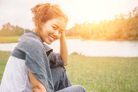 Asian women relax in the holiday. sit relax on a green pasture.の写真素材