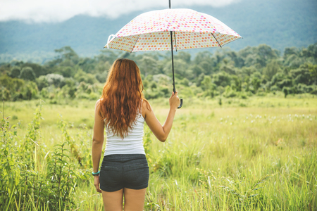 Asian women travel relax in the holiday. Running umbrella sunshine on a green pasture.の写真素材