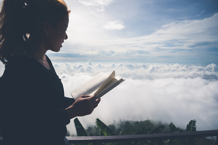 Women relax Read morning book good weather sky Mist. On the mountains, the morning atmosphere.の写真素材