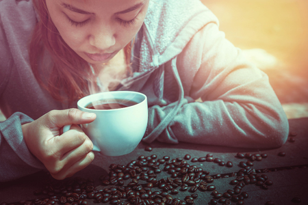 Women drink coffee On the wooden table floor there is a coffee bean.の写真素材