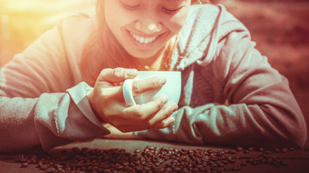 Women drink coffee On the wooden table floor there is a coffee bean.の写真素材