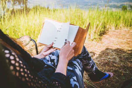 Asian women travel relax in the holiday. camping on the Mountain. sit write a note on the chair. Thailandの写真素材