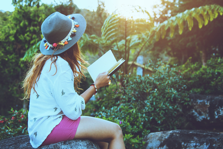Asian woman travel nature. Travel relax. Study read a book. Nature Education Write a note At public park in summer. In Thailandの写真素材