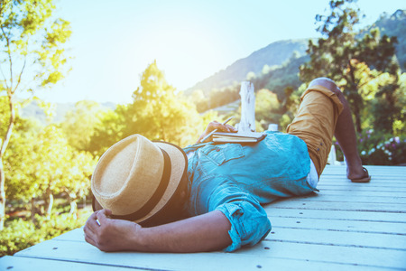 Asian man travel nature. Travel relax. Study read a book. Nature. sleep relax. At public park in summer. In Thailandの写真素材