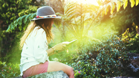 Asian woman travel nature. Travel relax. Study read a book. Nature Education Write a note At public park in summer. In Thailandの写真素材