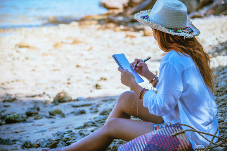 Asian woman travel nature. Travel relax. Study read a book. Nature Education Write a note. On the beach. In the summer. Thailandの写真素材
