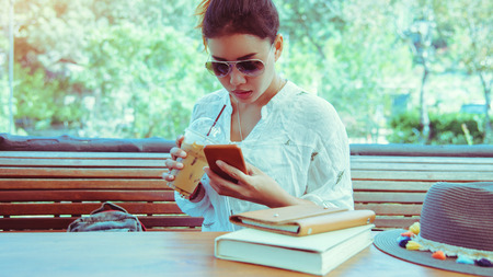 Asian woman travel nature. Travel relax. Hands are holding the phone. In the coffee shop.