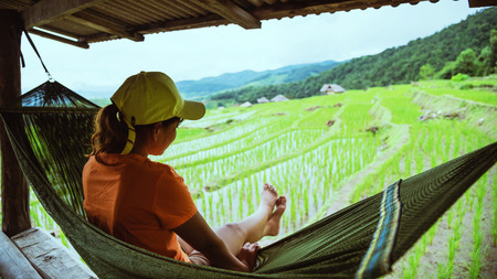Asian woman travel nature. Travel relax. Relax in the hammock the balcony of the resort. View of the field on the Moutain in summer. Thailandの写真素材
