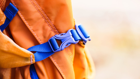 Close-up detail of locked blue convenient plastic clasp of backpack yellow.