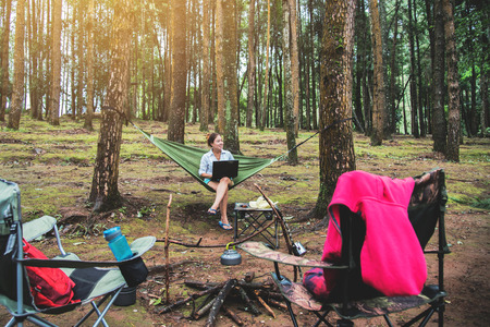 Asian women travel natural relax . Sitting working using a notebook. in the hammock. campsite on the national park  Doi inthanon at Chiangmai. in Thailandの写真素材