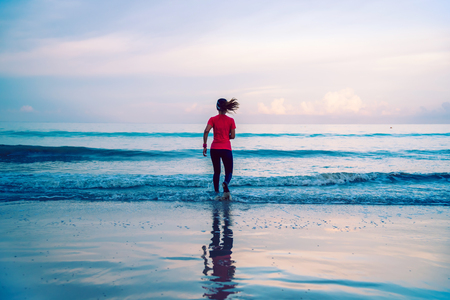 Girl running workout jogging on the beach in the morning. relax and happy with running on the sea. in summerの写真素材