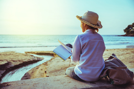 Asian woman travel nature. Travel relax study read a book and write a note on the beach. In the summer. Thailandの写真素材