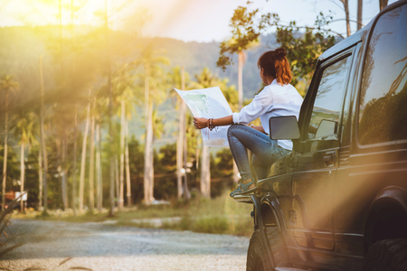 woman travel relaxing nature mountain map navigation. Sit on the car and browse the map.の写真素材