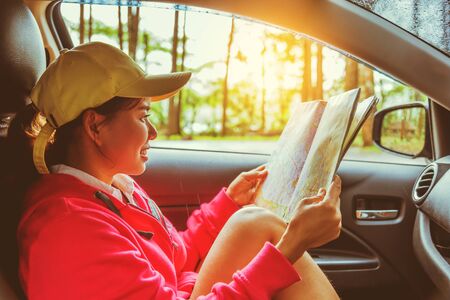 Asian women travel relax in the holiday. Traveling by car park. View map for Nature tours during the rainy season.の写真素材