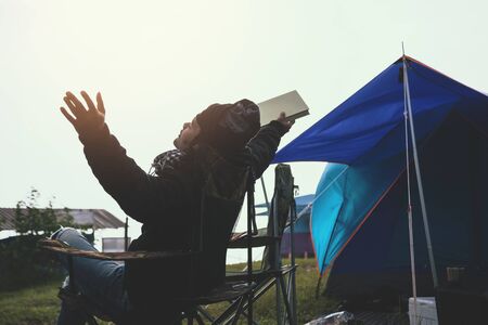 Asian man travel relax in the holiday. camping on the Mountain. sit read a book on the chair. Thailandの写真素材