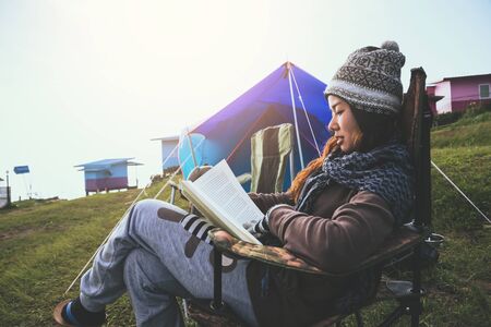 Asian women travel relax in the holiday. camping on the Mountain. sit read a book on the chair. Thailandの写真素材
