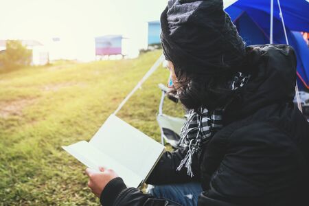 Asian man travel relax in the holiday. camping on the Mountain. sit read a book on the chair. Thailandの写真素材