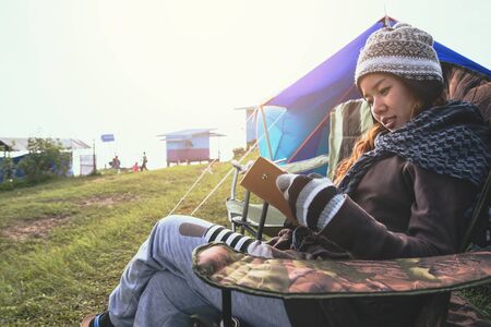 Asian women travel relax in the holiday. camping on the Mountain. sit write a note on the chair. Thailandの写真素材