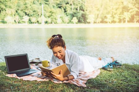 Women sitting a relax working with a notebook and lying reading a book during a relax in the park....