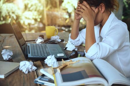 asian woman sitting working at home on vacation. Use working with notebook. Feeling very stressed and headaches with work done.の写真素材