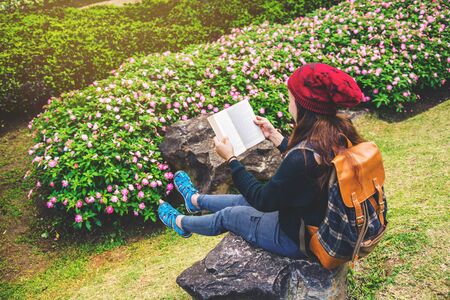 woman travel nature in the flower garden. relax sitting on rocks and reading books In the midst of nature at national park doi Inthanon.の写真素材