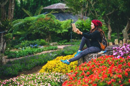 woman travel nature in the flower garden. relax sitting on rocks and reading books In the midst of nature at national park doi Inthanon.の写真素材