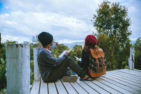 couple lover natural travel on the mountain, sitting relax reading books in the midst of nature on the white wooden bridge.の写真素材