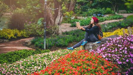 woman travel nature in the flower garden. relax sitting on rocks and reading books In the midst of nature at national park doi Inthanon.の写真素材
