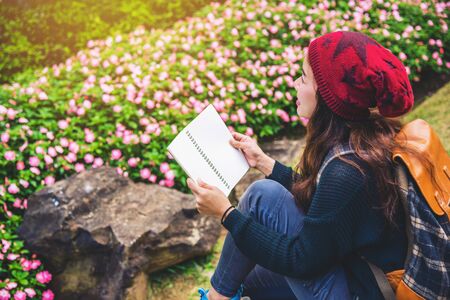 woman travel nature in the flower garden. relax sitting on rocks and reading books In the midst of...