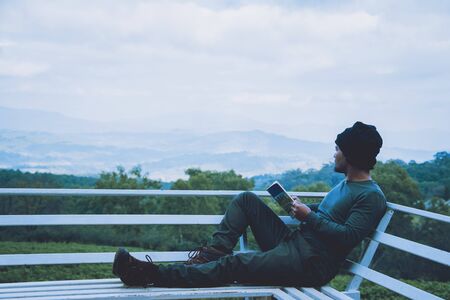 Man traveler is reading book travels nature on the mountain In the fresh air in the north, Chiang Mai in Thailand.の写真素材